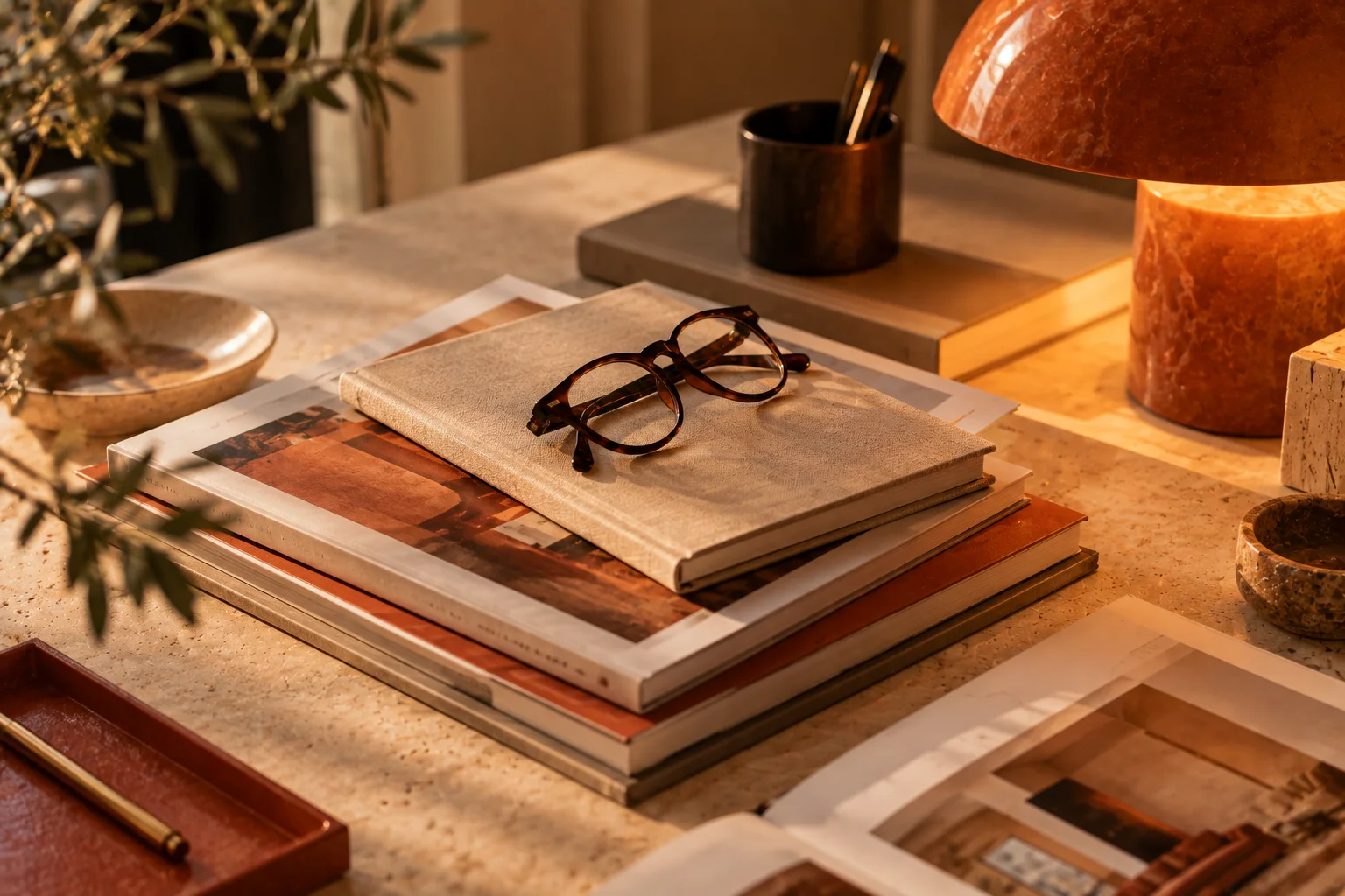 Une pile de livres de design et une paire de lunettes sur un bureau
